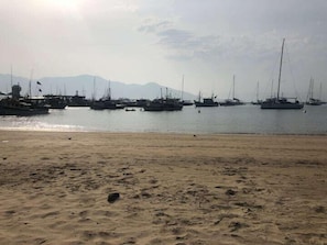 A sandy beach with several boats docked in the background.