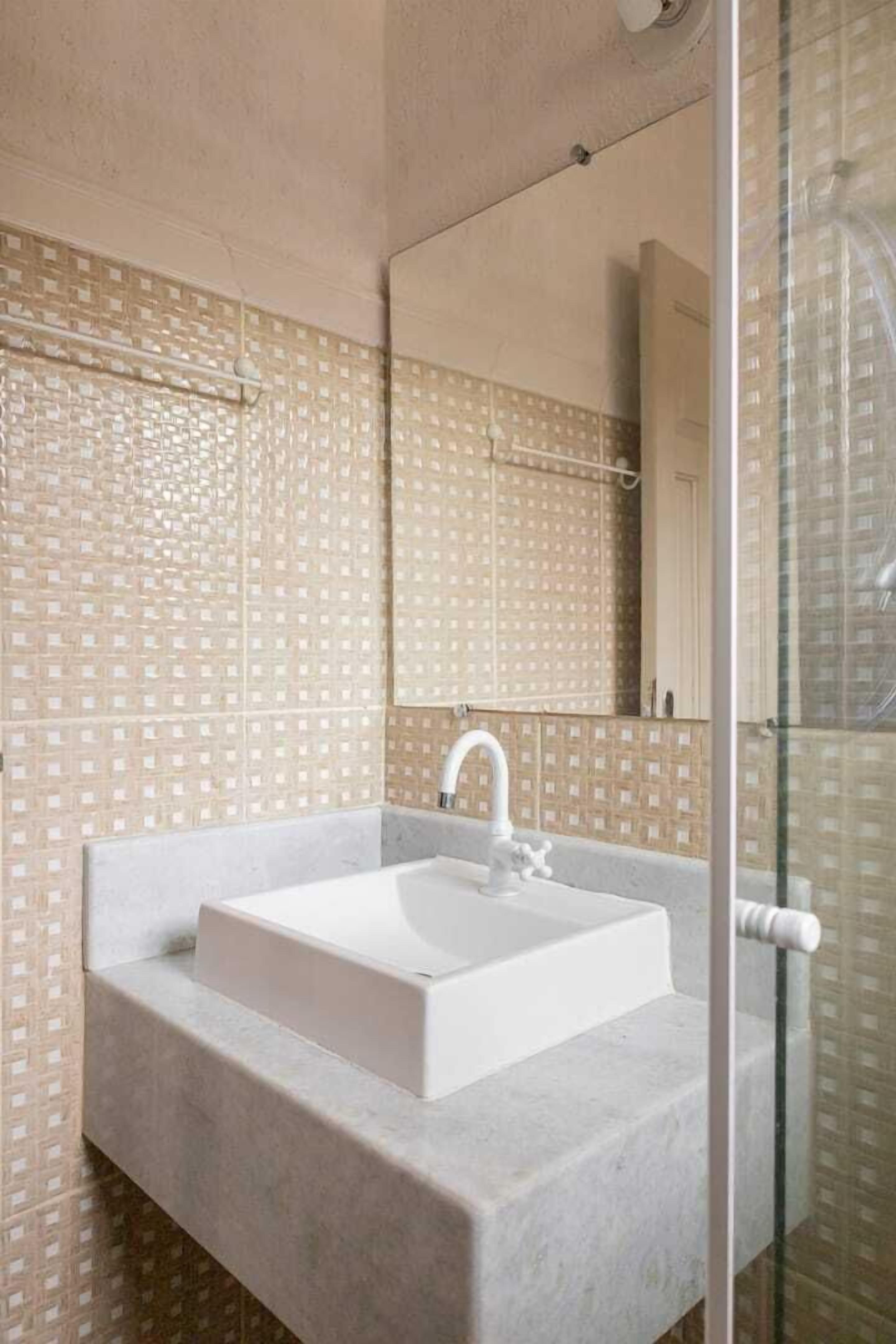 Un baño con un lavamanos blanco, un espejo y baldosas decorativas en las paredes.