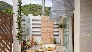 A modern outdoor space with a wooden fence, a glass door, and a variety of potted plants. - Casinha da Vila (Ilhabela)