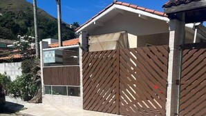 A residential building with a gated entrance, a tiled roof, and a paved driveway. - Casinha da Vila (Ilhabela)