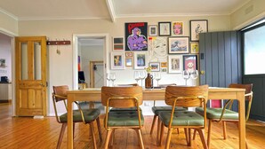 Un comedor con una mesa y sillas de madera, obras de arte en la pared y una puerta de madera.