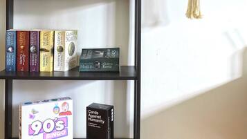 A bookshelf with books, a board game, and a plant.