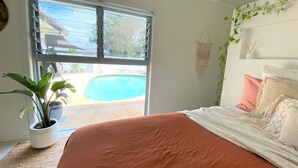 Una camera da letto con un letto grande, vista su una piscina e una pianta in vaso.