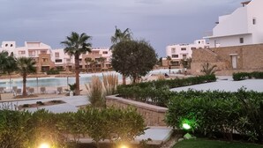 Un complexe hôtelier doté d’une piscine, de palmiers et de bâtiments modernes.
