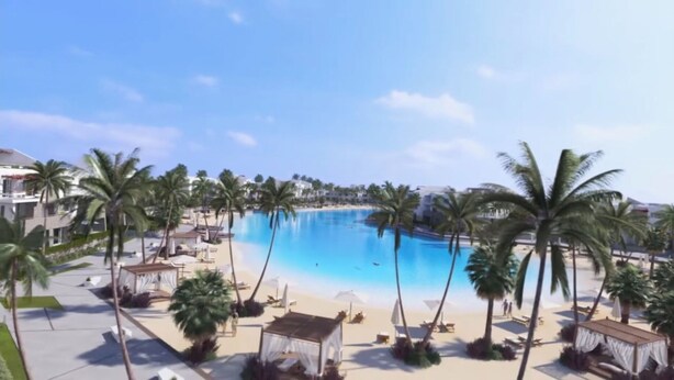 Un complexe hôtelier doté d’une grande piscine, entourée de palmiers et de chaises de plage.