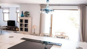 Una cucina moderna con un piano di lavoro in marmo, un piano cottura a induzione nero e un lampadario.