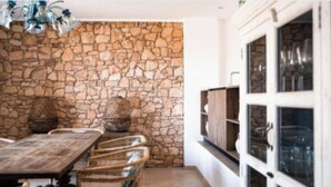 Un muro in pietra, mobili in vimini e un armadietto con vetrate.