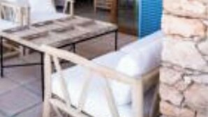 Un'area esterna con tavoli e sedie, un muro in pietra e vista sull'interno.