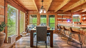 A wooden cabin interior with a dining table, chairs, and a bar area. - Pet Friendly · Hot Tub · Mins to Dollywood · Views (Pigeon Forge)