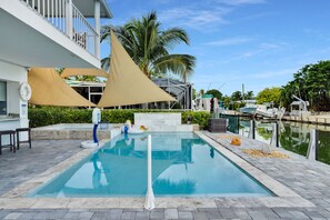 A swimming pool with a lifeguard chair, a sunshade, and a water slide.