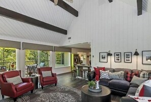 Relax in a spacious living area with a high ceiling and exposed beams, featuring a sofa set, armchair, and coffee table.