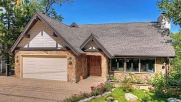 Situated in a wooded area, this two-story home features a garage and a beautifully landscaped garden.