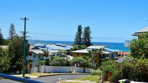 A coastal residential area with houses, a clear sky, and a view of the ocean.