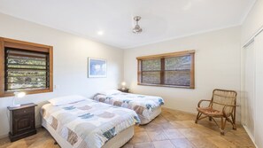 Ein Schlafzimmer mit zwei Betten, einem Sessel und einem Deckenventilator.