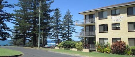 A two-story building named 'Finders Lodge' with a balcony on the second floor, surrounded by greenery and a clear sky.