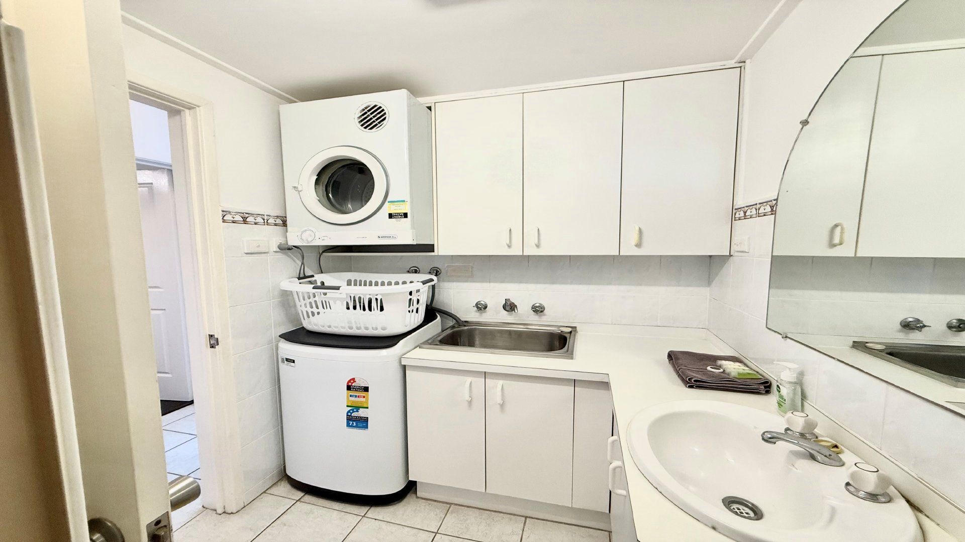 Une cuisine de taille réduite, équipée d’un lave-linge, d’un évier et de placards.