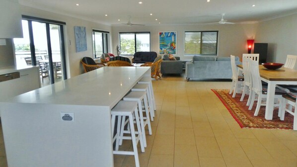 A spacious living area with a dining table and chairs, a sofa, and a kitchen area with a large island.