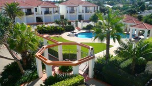 A resort with a swimming pool, palm trees, and a gazebo.