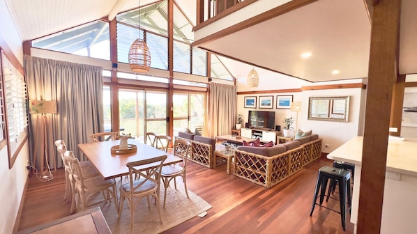 A spacious living area with a dining table, chairs, a sofa, and a television. - Spookys 5 - Lifestyle Yamba (ANGOURIE)
