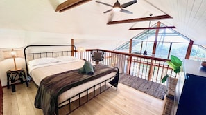 A bedroom with a bed, a nightstand, a lamp, a ceiling fan, and a view through a window. - Spookys 5 - Lifestyle Yamba (ANGOURIE)