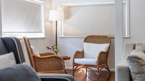 Una stanza con mobili in vimini, una lampada e un vaso con fiori.