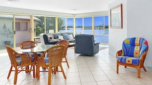 Enjoy a serene view of the lake from this spacious room with a large window, featuring a round dining table and comfortable seating areas.