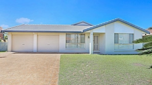 Stunning single-story home with a flat roof, covered driveway, and beautifully manicured lawn.