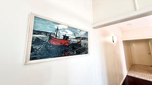 Ein Flur mit einem gerahmten Gemälde von Booten an der Wand.
