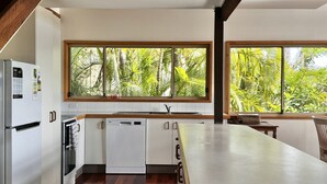 A modern kitchen with a built-in dishwasher, a refrigerator, and a window with a view of lush greenery. - Drift - Lifestyle Yamba (ANGOURIE)