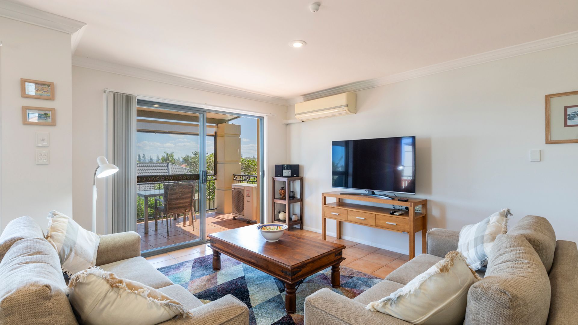 Sala de estar com sofá, mesa de centro, TV de tela plana e varanda com vista.