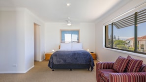 A bedroom with a bed, a nightstand, a window with a view, and a ceiling fan. - Meridian 5 - Lifestyle Yamba (YAMBA)