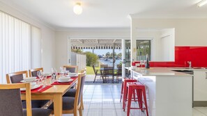 Une cuisine moderne avec un mur de fond rouge, un coin repas offrant une vue sur l’extérieur et un vaste espace de vie.
