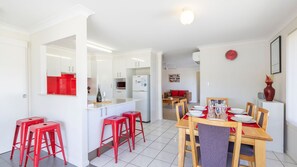 Una cucina moderna con mobili bianchi, un'isola centrale e sgabelli rossi.