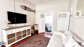 A room with a television, a white cabinet with baskets, a patterned rug, and a bed. - Surfside - Lifestyle Yamba (YAMBA)