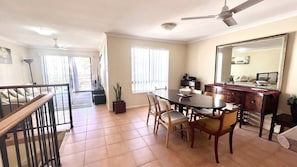 A dining area with a table and chairs, a ceiling fan, and a large mirror on the wall.