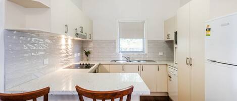 A compact kitchen with a central island, a window above the sink, and wooden chairs.