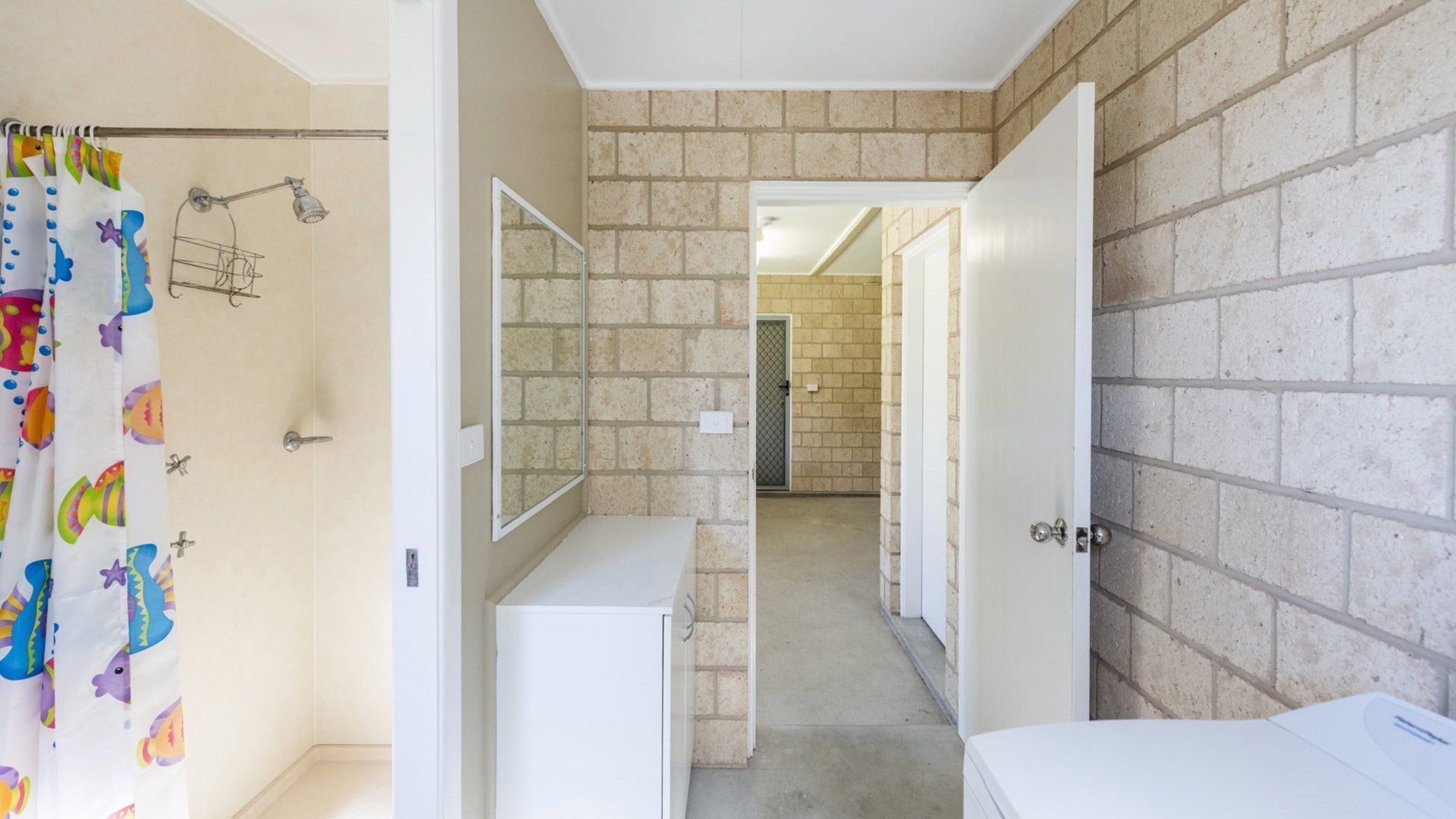 A bathroom with a shower, a mirror, and a toilet.