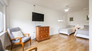 A bedroom with a wooden dresser, a bed, a chair, and a television mounted on the wall.