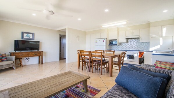 A compact living space with a dining area, kitchenette, and a television.