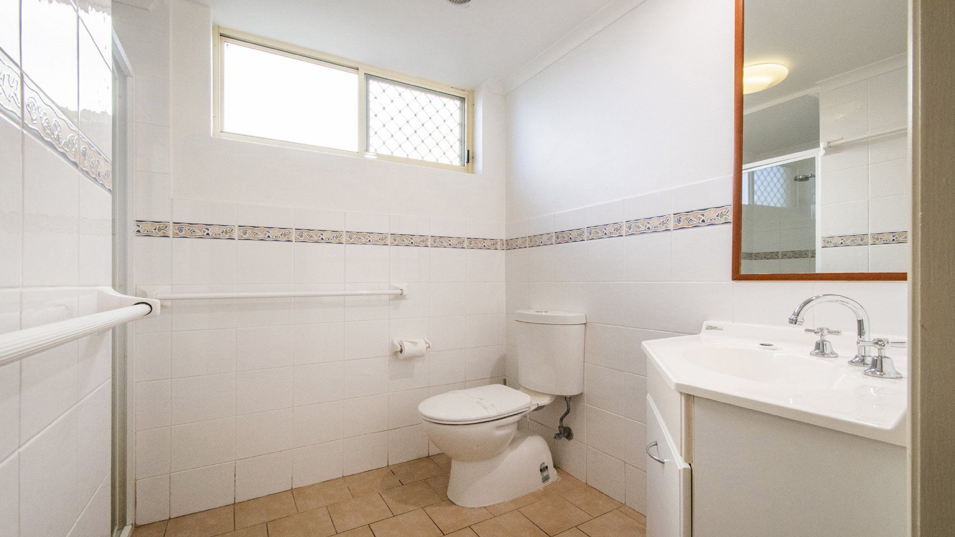 A bathroom with a toilet, sink, and window.