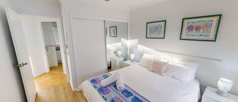 A bedroom with a bed, bedside tables, a ceiling fan, and two framed pictures on the wall.