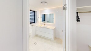 Un baño moderno con un tocador blanco, un lavabo redondo e iluminación integrada en el espejo.