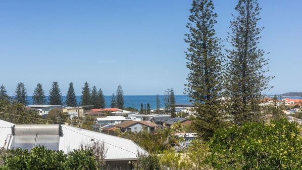 Una zona residencial costera con casas, cielo despejado y vista al mar.