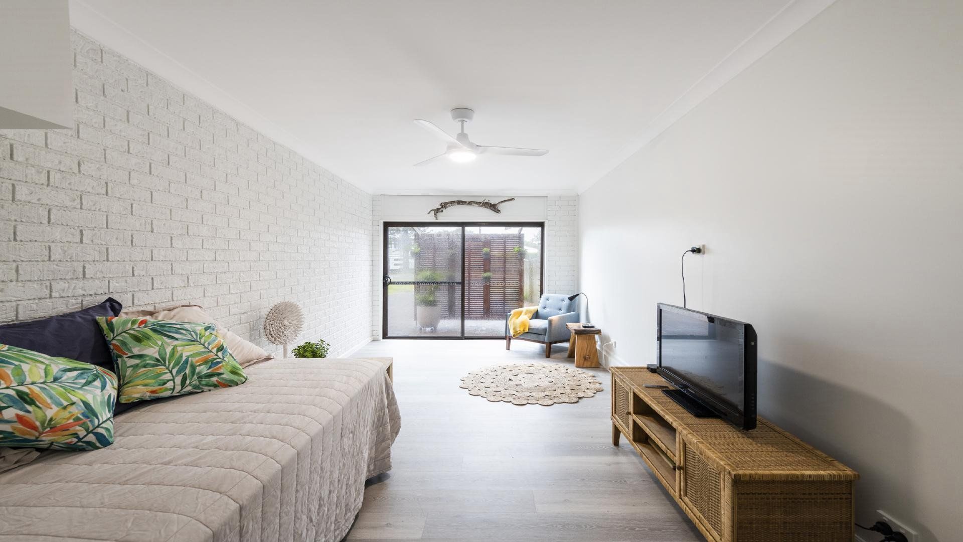 A modern living room with a bed, a television, and a large window.