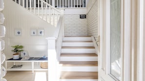 A staircase with white railings and wooden steps, a welcome sign, and a bench with decorative items.