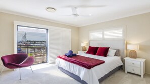 A hotel room with a bed, a chair, a nightstand, and a view of a marina through the window. - Marina Views - Lifestyle Yamba (YAMBA)