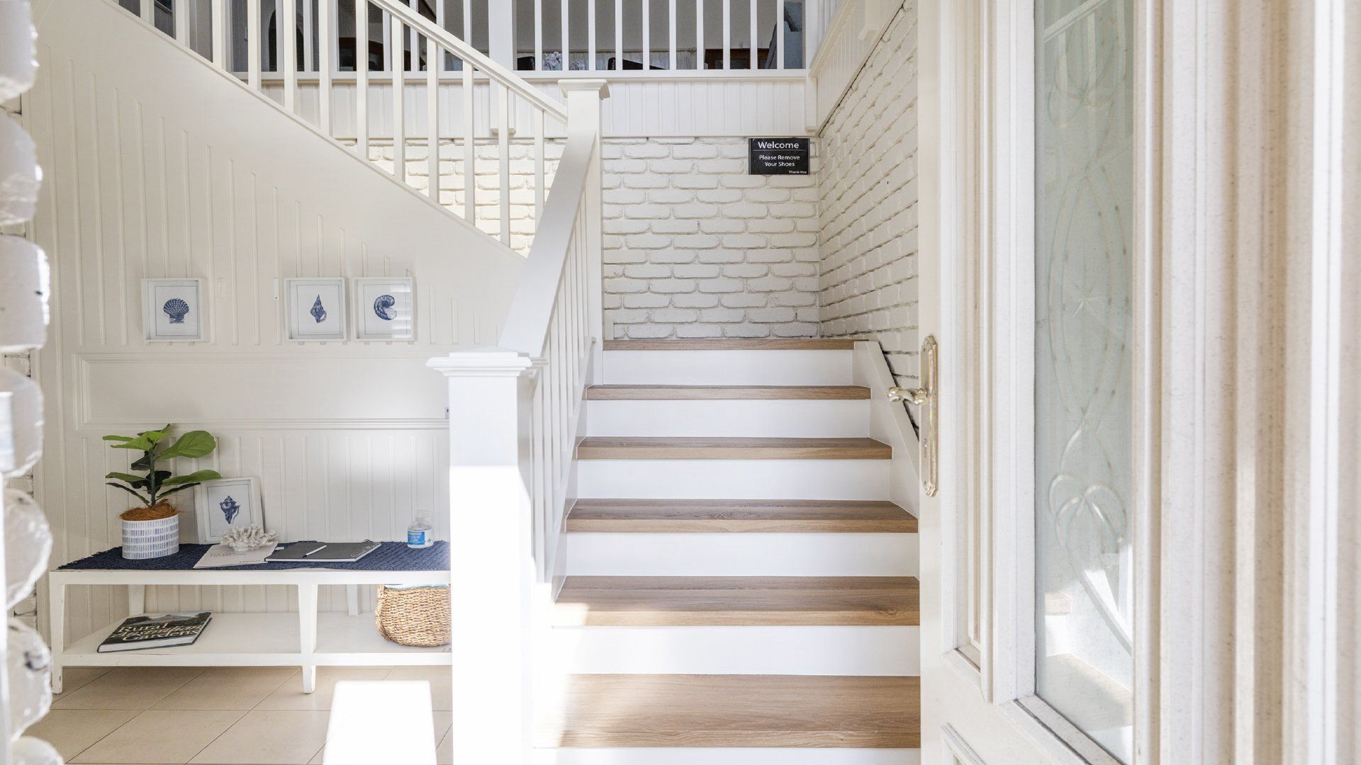 A staircase with white railings and wooden steps leading to a landing with a welcome sign.