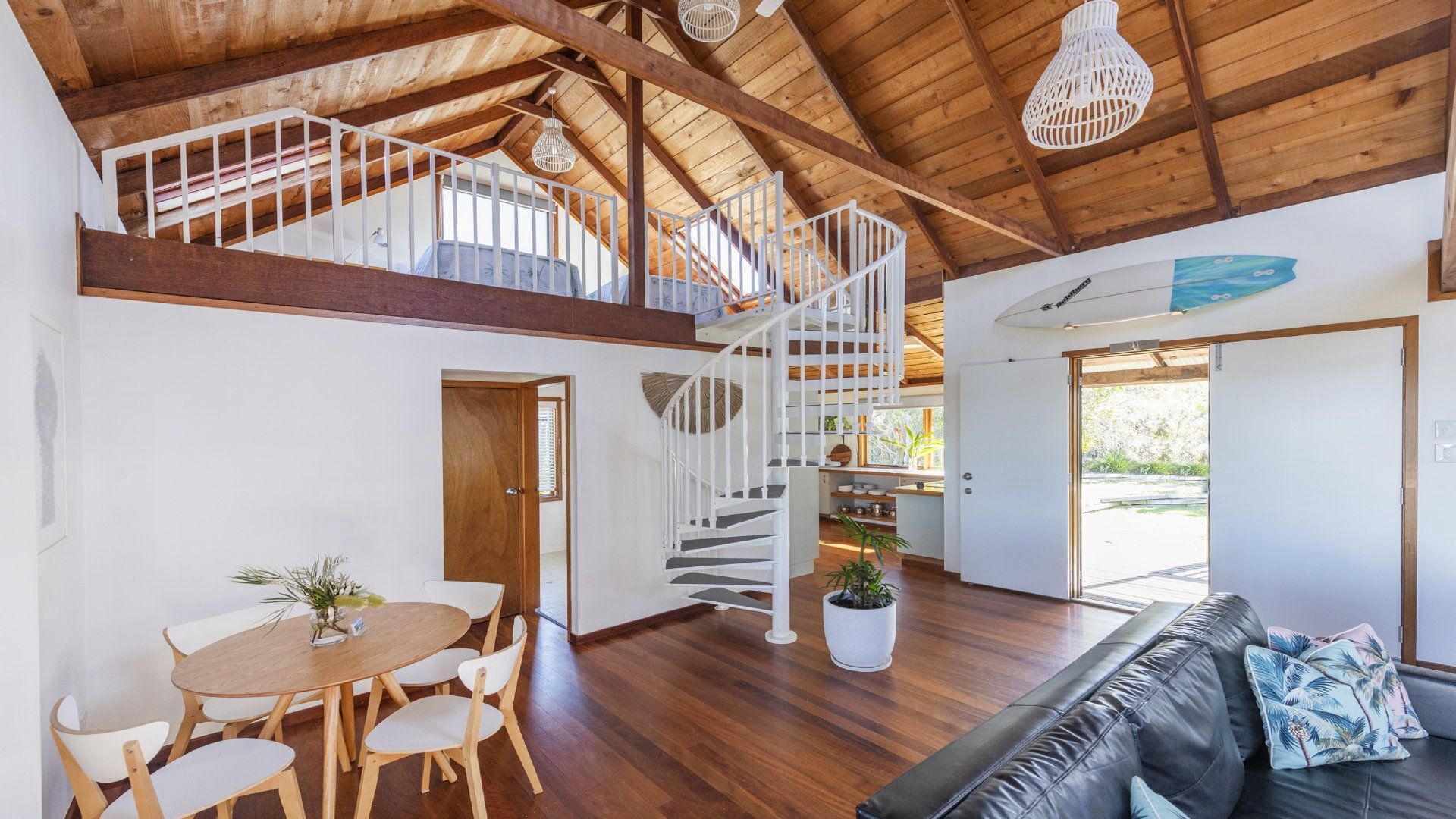 A spacious interior with a wooden staircase, a dining area, and a living room with a sofa.