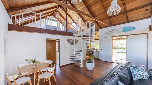 A spacious interior with a wooden staircase, a dining area, and a living room with a sofa. - The Point - Lifestyle Yamba (ANGOURIE)