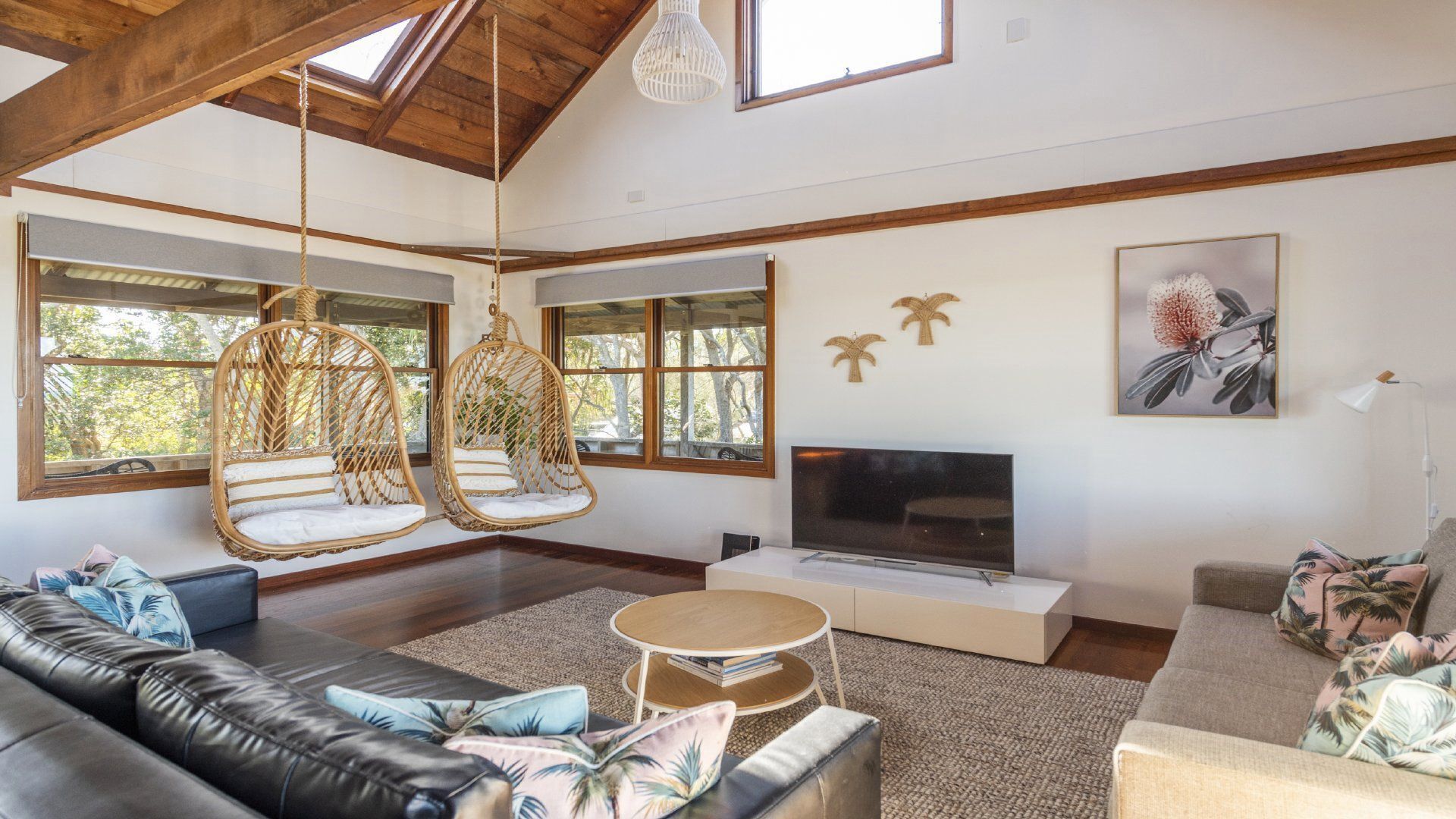 A spacious living room with a large sofa, hanging chairs, a flat-screen TV, and a fireplace.